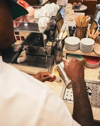 Un barista prépare un café derrière la machine espresso du comptoir.