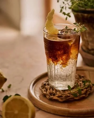 Kafé Armor : espresso tonic servi sur glace dans un grand verre, zeste de citron vert et brin de thym.