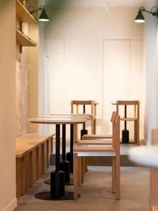 Une table d'étude en bois clair avec banquette, éclairée par deux lampes vertes.
